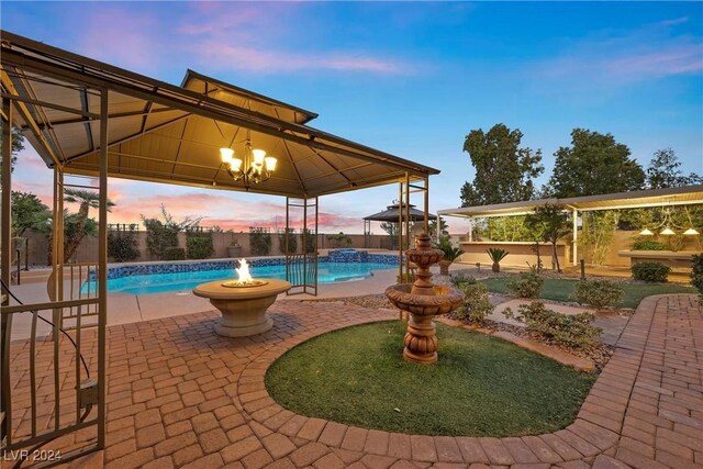 pool at dusk with a gazebo, a patio, and pool water feature