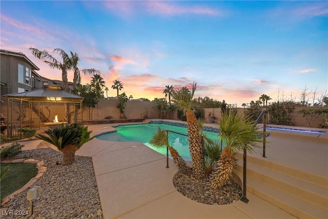 pool at dusk featuring a gazebo and a patio area