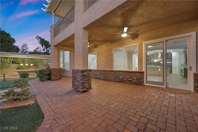 patio terrace at dusk featuring a balcony and ceiling fan