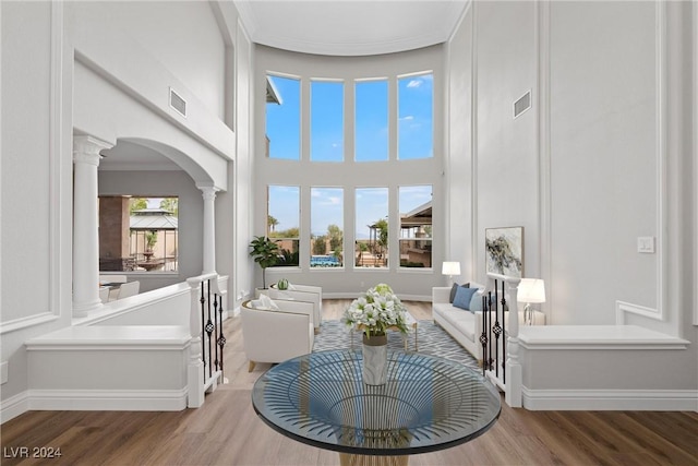 living area with visible vents, decorative columns, and wood finished floors