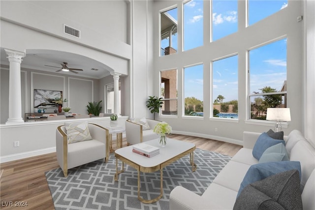 interior space featuring arched walkways, wood finished floors, visible vents, baseboards, and ornate columns