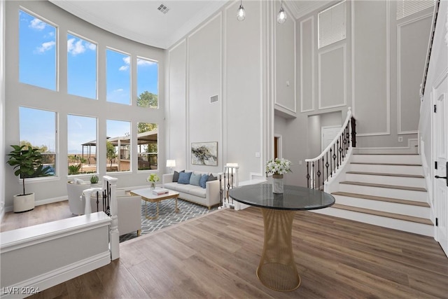 living area with visible vents, a decorative wall, stairway, and wood finished floors