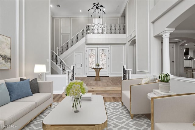 living area featuring arched walkways, stairway, ornamental molding, wood finished floors, and a notable chandelier