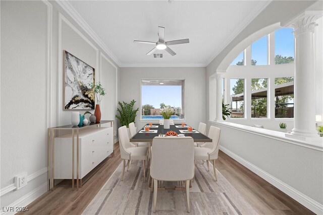 dining space featuring crown molding, baseboards, wood finished floors, and ornate columns