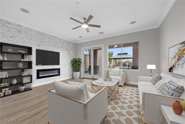 living area featuring visible vents, ceiling fan, ornamental molding, light wood-style floors, and a fireplace