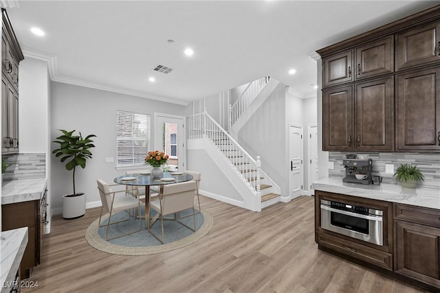 dining area with ornamental molding, stairway, light wood-style flooring, and baseboards