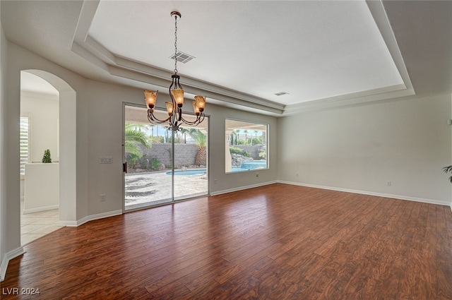 spare room featuring a notable chandelier, wood-type flooring, and a tray ceiling