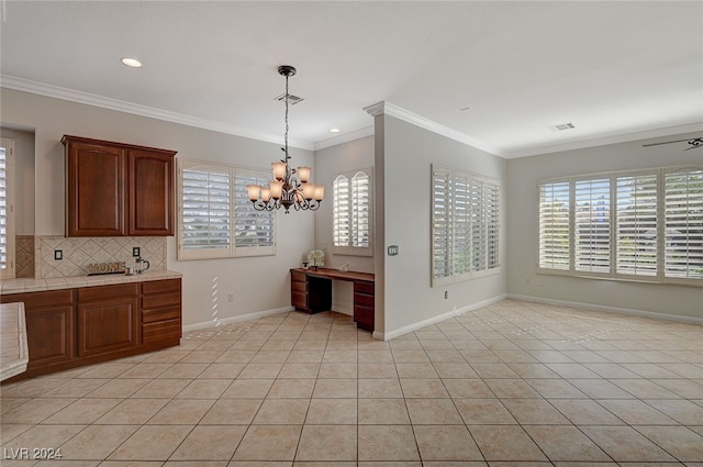 kitchen with built in desk, decorative backsplash, hanging light fixtures, ornamental molding, and light tile patterned floors