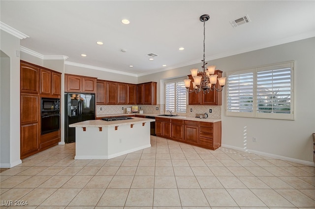 kitchen with hanging light fixtures, sink, black appliances, a center island, and crown molding