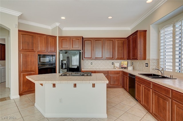 kitchen featuring black appliances, sink, a kitchen island, tile countertops, and crown molding