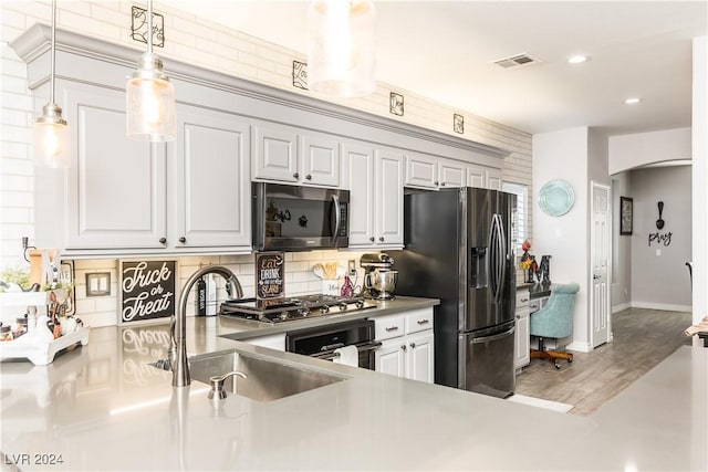 kitchen with hanging light fixtures, a sink, stainless steel appliances, backsplash, and visible vents