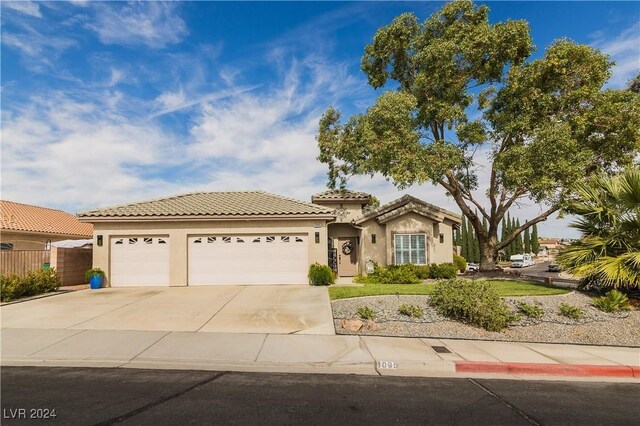 mediterranean / spanish-style home with a garage, fence, stucco siding, a tiled roof, and driveway