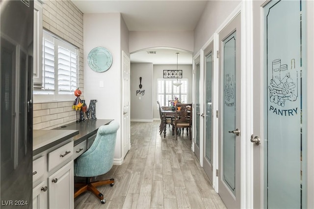 home office featuring arched walkways, baseboards, light wood finished floors, and visible vents