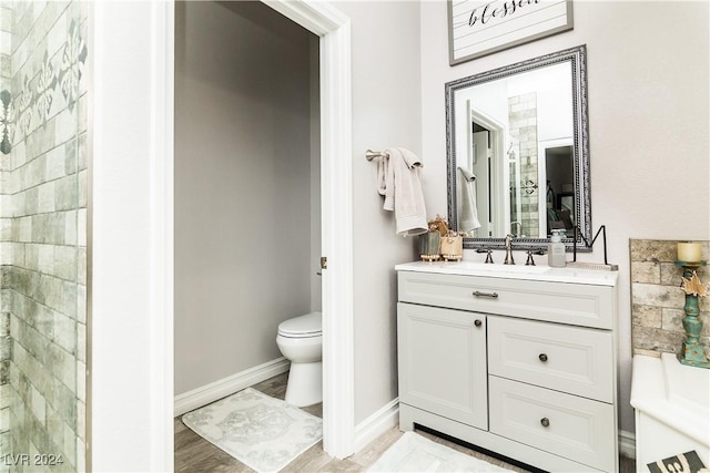 full bath with vanity, baseboards, wood finished floors, and toilet