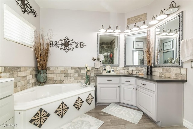 bathroom with a washtub, wood finished floors, and vanity