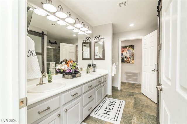 bathroom featuring visible vents, a sink, stone finish floor, and a shower stall