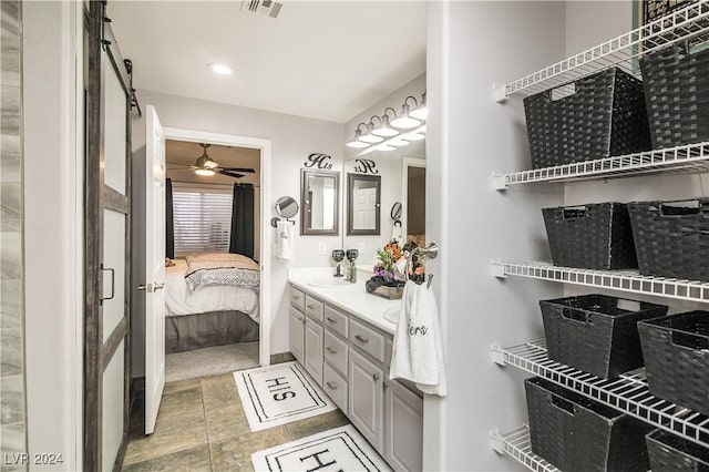 ensuite bathroom featuring visible vents, double vanity, ceiling fan, connected bathroom, and a sink