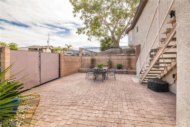 view of patio / terrace featuring stairway, a fenced backyard, and outdoor dining space