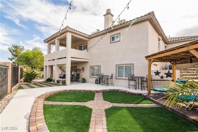 rear view of house with a patio, fence, a balcony, and stucco siding