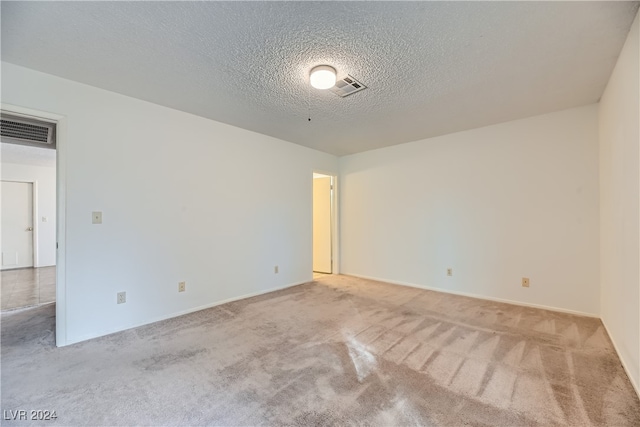 empty room with a textured ceiling and light carpet