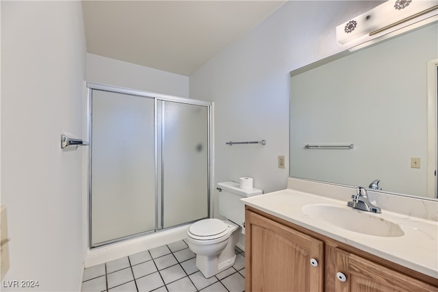 bathroom with toilet, tile patterned floors, vanity, and a shower with door