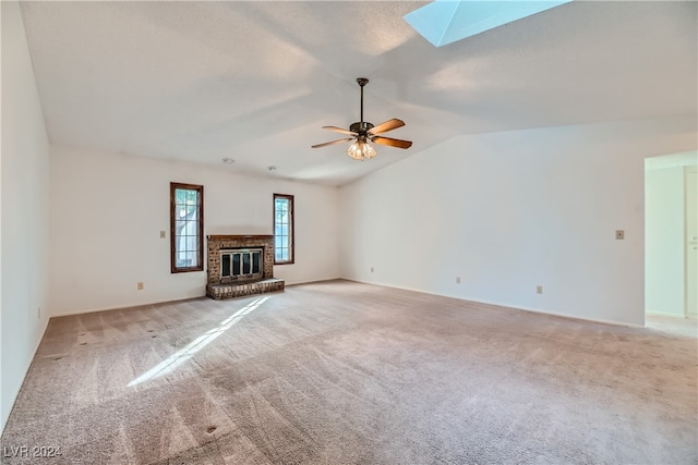 unfurnished living room featuring a brick fireplace, ceiling fan, light carpet, and lofted ceiling with skylight