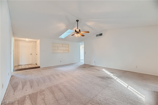 unfurnished living room with ceiling fan, light carpet, and lofted ceiling with skylight