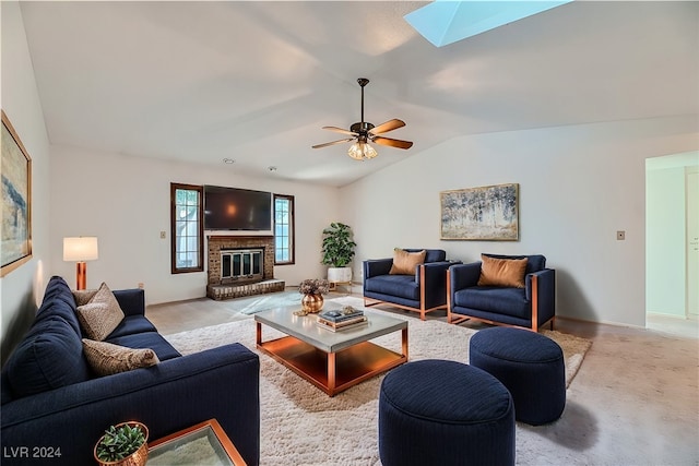 living room featuring a fireplace, vaulted ceiling with skylight, light colored carpet, and ceiling fan