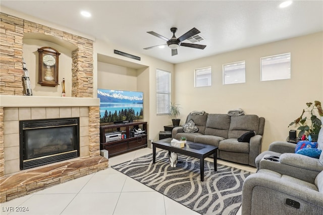 tiled living room featuring a fireplace and ceiling fan