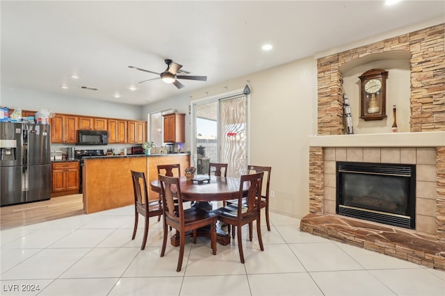 dining area with light tile patterned floors, a fireplace, and ceiling fan