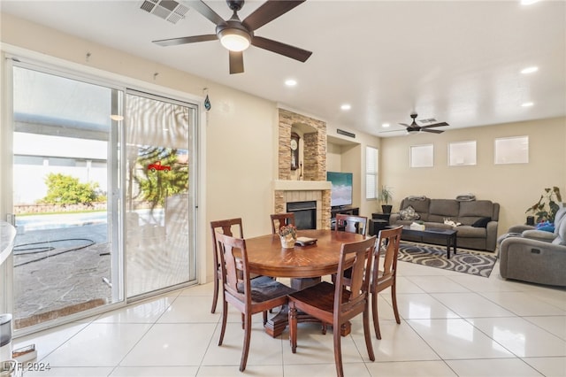 dining room with light tile patterned flooring, a fireplace, and ceiling fan