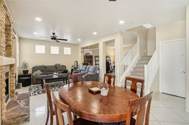 tiled dining area with ceiling fan and a fireplace