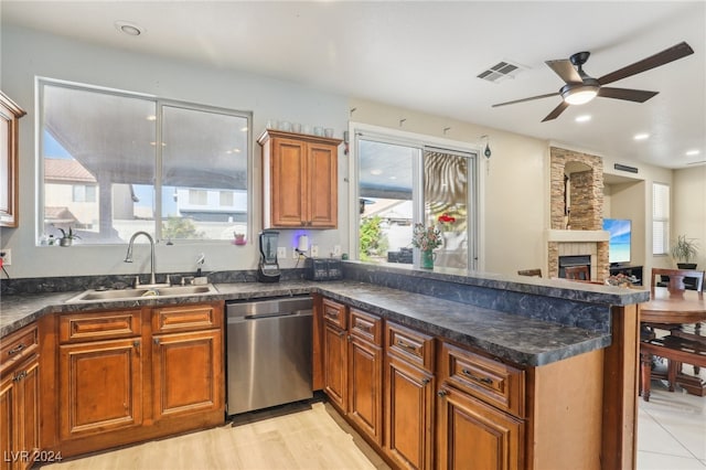 kitchen with sink, light wood-type flooring, a fireplace, ceiling fan, and stainless steel dishwasher