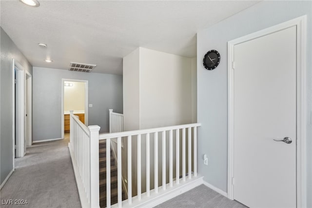 hall featuring light carpet and a textured ceiling