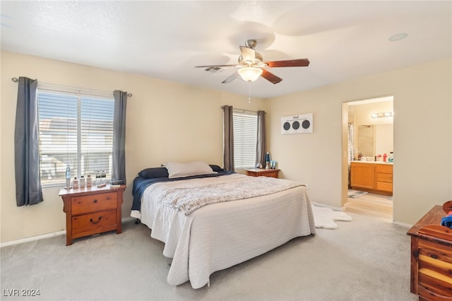 carpeted bedroom with ensuite bath and ceiling fan