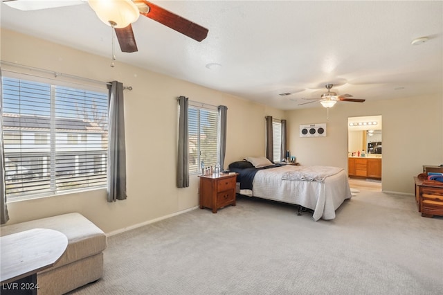 carpeted bedroom featuring ceiling fan, multiple windows, and ensuite bathroom