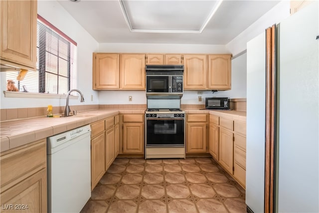 kitchen with tile countertops, light brown cabinets, sink, and white appliances