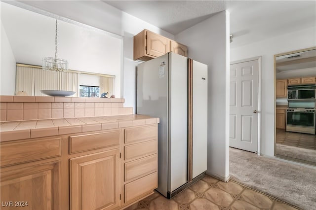 kitchen featuring white appliances, light brown cabinetry, hanging light fixtures, tile counters, and an inviting chandelier