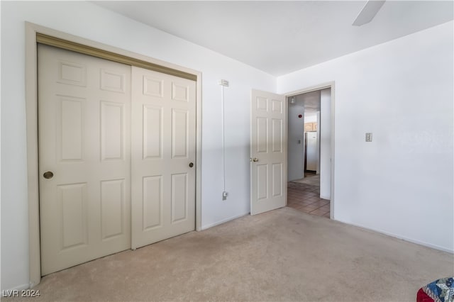 unfurnished bedroom with light colored carpet, a closet, and ceiling fan