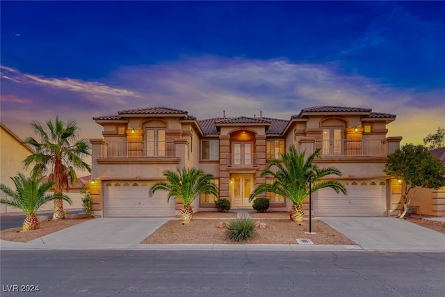 mediterranean / spanish-style home featuring a balcony, french doors, and a garage