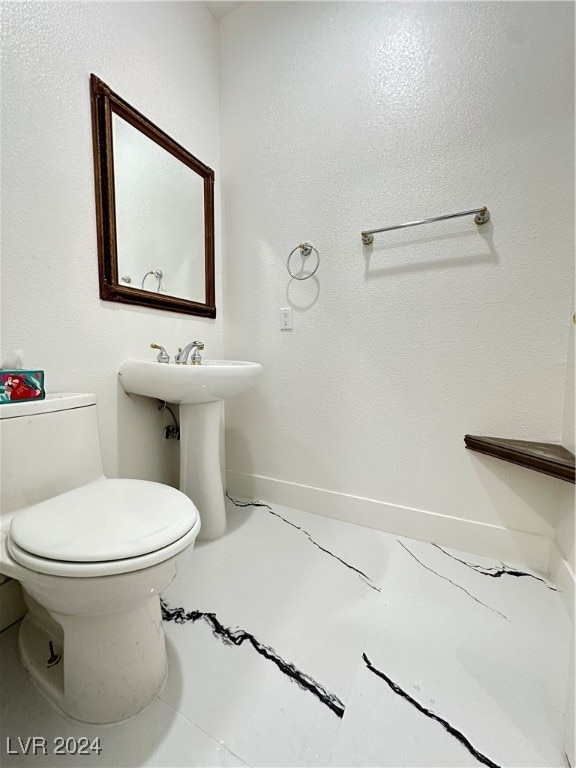 bathroom featuring toilet, sink, and tile patterned flooring