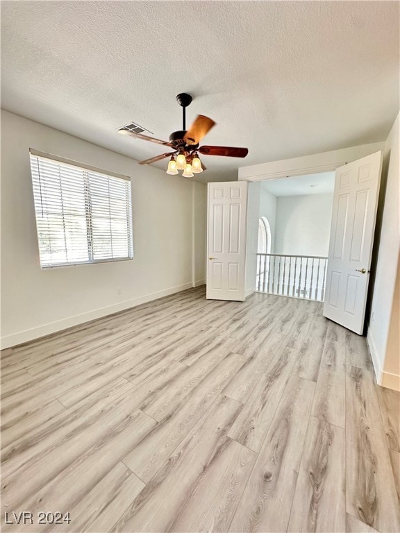 spare room featuring light hardwood / wood-style flooring, a textured ceiling, and ceiling fan