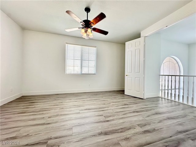 spare room featuring a healthy amount of sunlight, a textured ceiling, light wood-type flooring, and ceiling fan