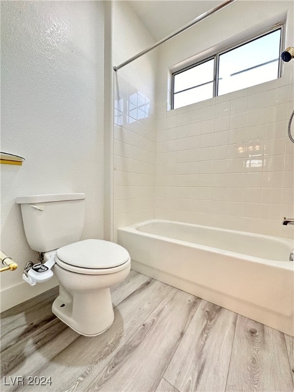 bathroom featuring toilet, tiled shower / bath, and hardwood / wood-style floors