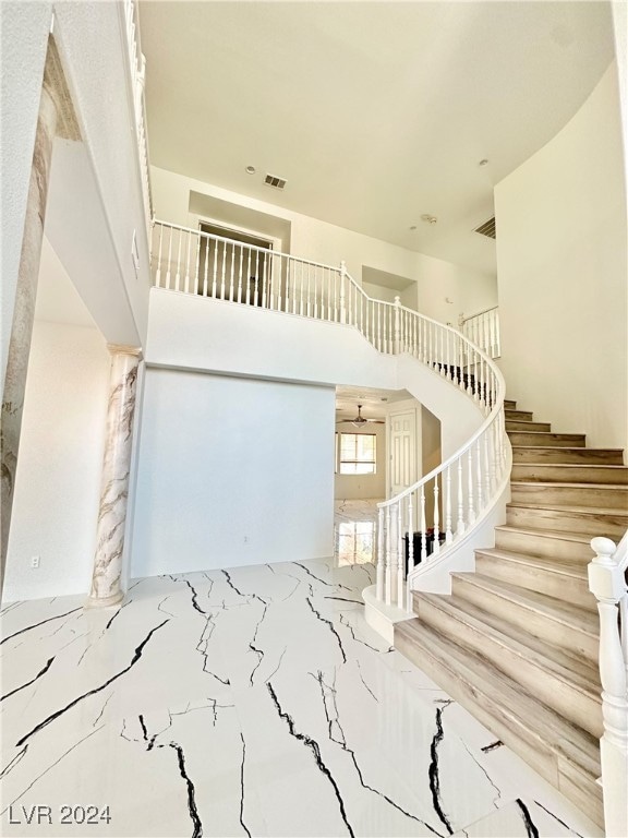 staircase with a high ceiling and ceiling fan