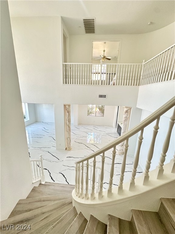 stairway featuring a high ceiling, hardwood / wood-style flooring, and ceiling fan