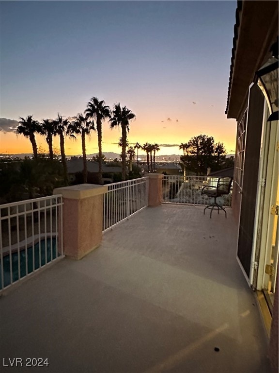 patio terrace at dusk featuring a balcony