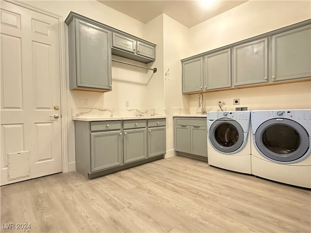 washroom featuring sink, washer and dryer, cabinets, and light wood-type flooring