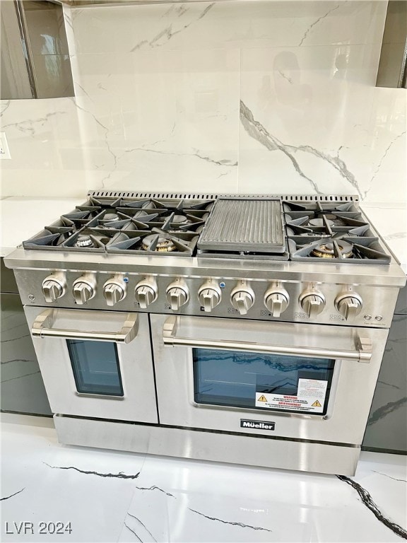 interior details with light stone counters, double oven range, and backsplash