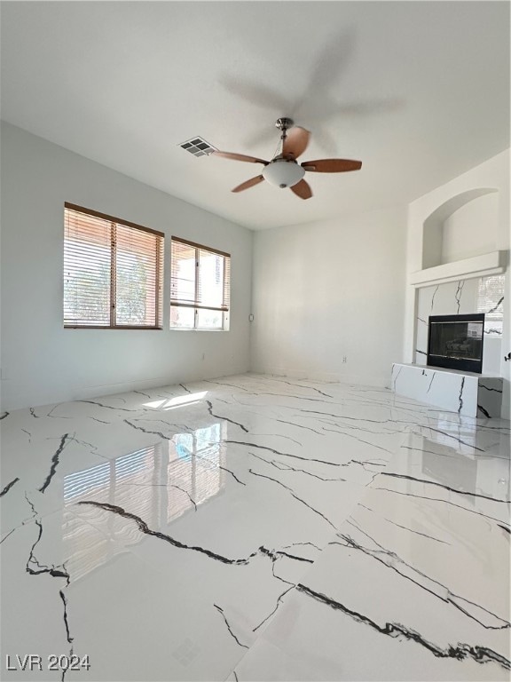 unfurnished living room with a fireplace and ceiling fan